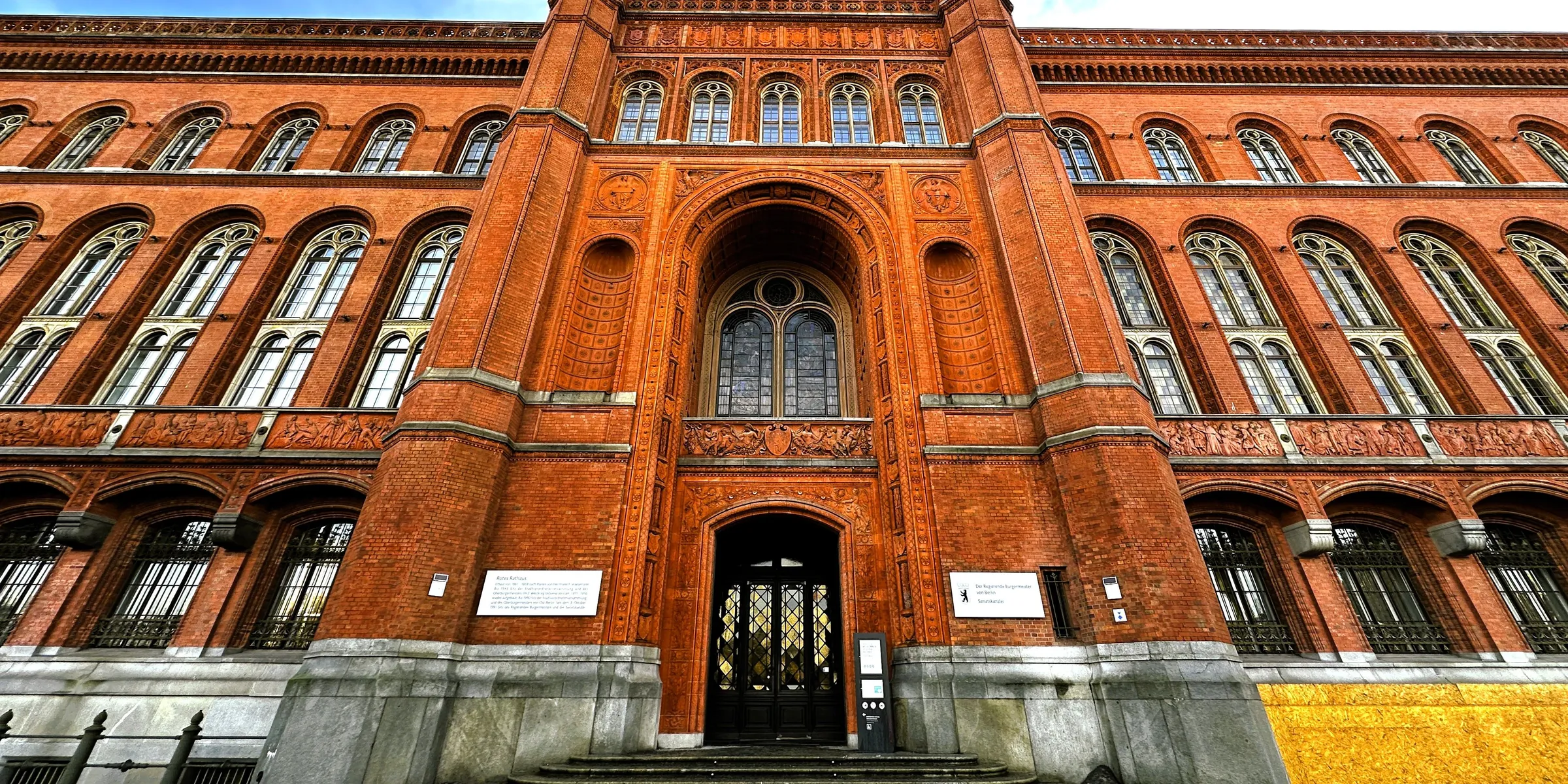 Backsteinfassade und Haupteingang des Roten Rathauses in Berlin unter blauem Himmel