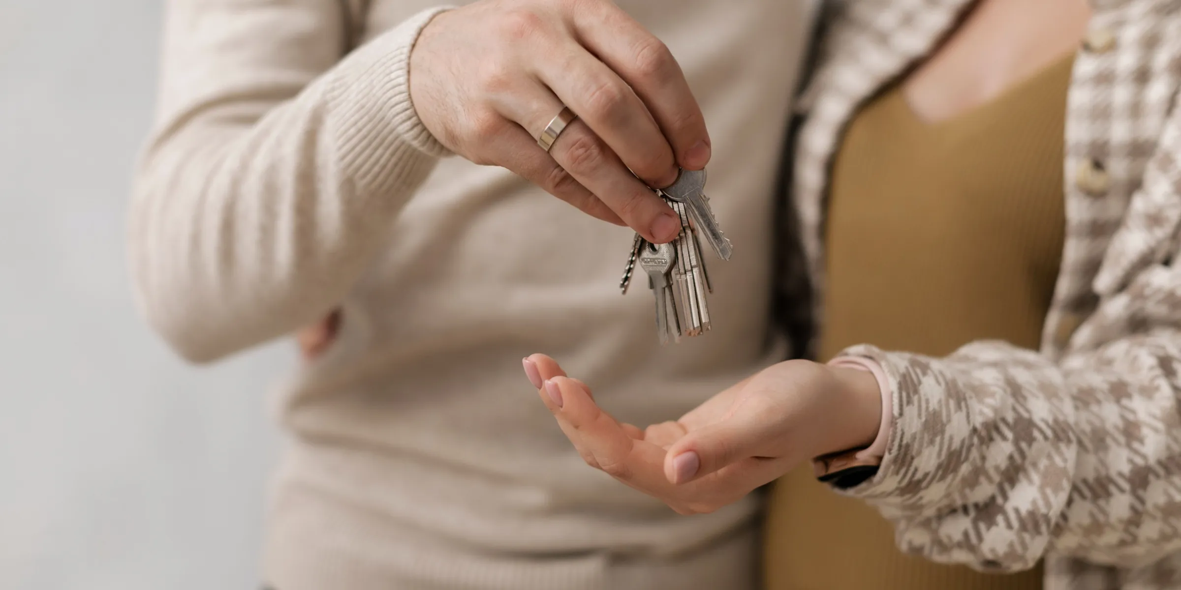 Eine Hand übergibt einen Wohnungsschlüssel in die geöffnete Hand einer anderen Person